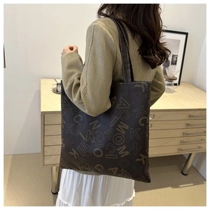 Close-up of dark brown leather tote bag featuring detailed letter prints and white stitching