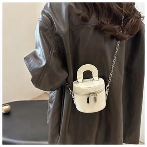 Detail view of mini white leather bucket bag with silver chain strap and top handle