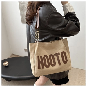 Dettaglio della borsa tote beige con scritta HOOTO e tracolla in catena di metallo