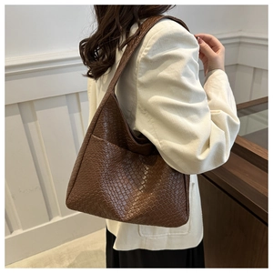 Detailed shot of dark brown woven texture shoulder bag worn by model in retro style