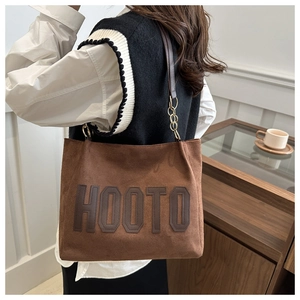 Detail of a brown suede tote bag with HOOTO logo and chain strap for daily commute