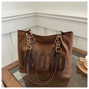 Dettaglio borsa tote in pelle scamosciata marrone con scritta HOOTO e catena oro