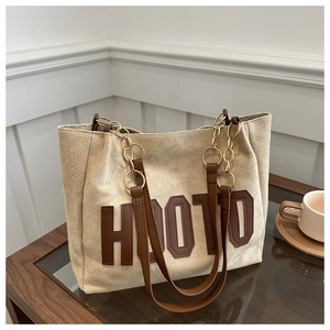 Dettaglio della borsa tote in tela beige con patch marrone e catena in metallo dorato