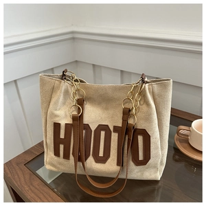 Dettaglio borsa tote in pelle scamosciata beige con patch HOOTO e catena in metallo