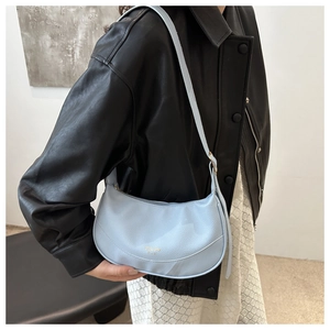 Detailed texture of baby blue leather crescent bag worn with a black leather jacket