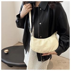 Close-up of beige crescent shoulder bag in pebble leather with adjustable strap