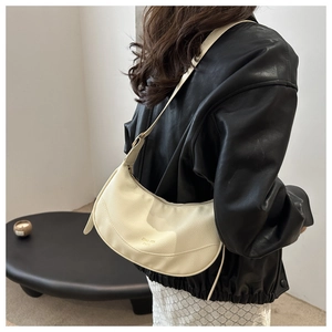 Close-up of beige moon bag in lychee leather showing the branded texture on a model