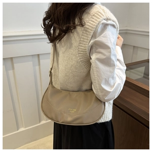 Detail of lychee textured leather crescent hobo bag with gold logo on a female model