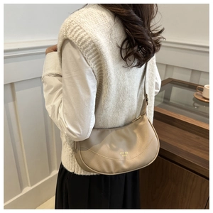 Model wearing a khaki pebble leather crescent bag with adjustable shoulder strap