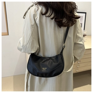 Detail of black pebbled leather dumpling bag worn with a beige trench coat