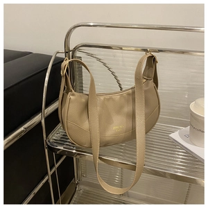Detail view of khaki patchwork crescent bag on a modern metal display shelf