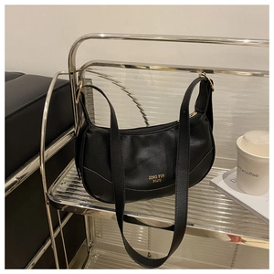 Detail view of black crescent bag featuring lychee grain texture and gold buckle