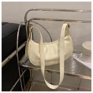 Detailed close-up of cream textured leather hobo bag with gold logo and zipper