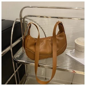 Detail of brown crescent bag showing lychee grain faux leather texture and gold hardware