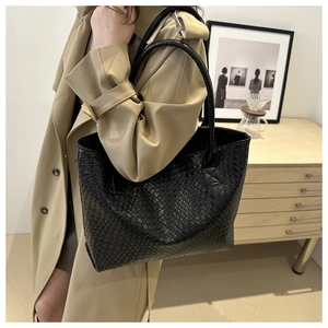 Detail shot of a black woven texture tote bag featuring long slim handles for daily commute