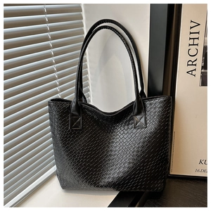 Close-up of woven texture and glossy synthetic leather on black tote bag