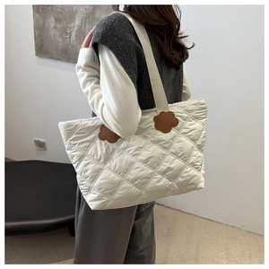 Close-up of white quilted tote bag with brown flower patch and puffy diamond texture