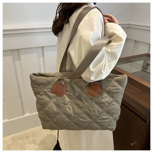 Detailed view of quilted khaki green nylon tote bag with leather flower accents on shoulder strap
