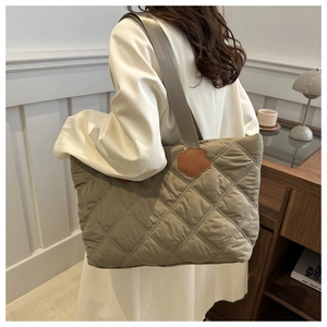 Close-up of khaki quilted tote bag with unique brown floral leather strap accents