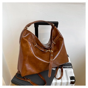 Detail einer großen braunen Kunstledertasche mit goldenen Beschlägen auf einem Koffer