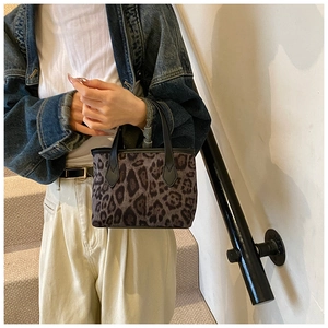 Dettaglio della mini borsa leopardata con manici in pelle nera e cuciture rinforzate