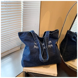 Vista dettagliata della borsa tote in denim blu scuro con ricamo bianco e doppi spallacci