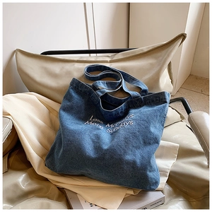 Detailed view of the 'Less Mondays More Sundays' embroidery on blue denim tote bag