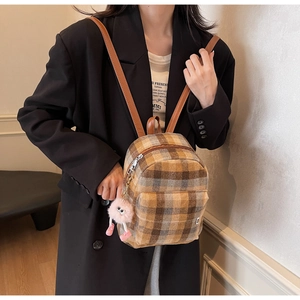 Detail of checkered mini backpack with leather straps and a pink plush doll pendant