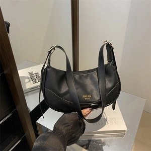 Chic black lychee leather crescent bag with gold hardware and a minimalist design