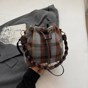 Close-up of vintage plaid bucket bag with woven handle and drawstring closure