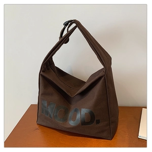 Detail of dark brown canvas tote bag featuring MOOD print on a wooden desk