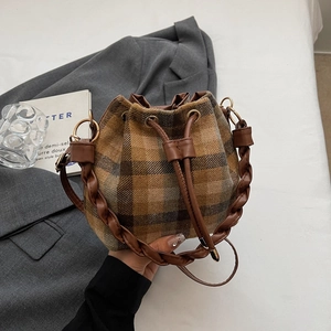 Detail of checkered wool bucket bag featuring leather drawstring and woven handle
