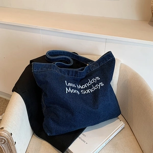 Borsa tote in denim blu scuro retrò con ricamo bianco su una sedia minimalista