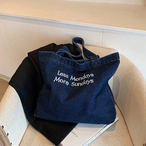 Borsa tote in denim blu scuro retrò con ricamo Less Mondays More Sundays sul divano