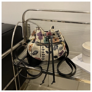 Detailed close-up of floral jacquard fabric and black leather on a drawstring bucket bag