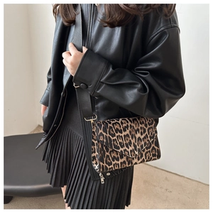 Fashionable leopard print crossbody bag with wide black shoulder strap and silver hardware
