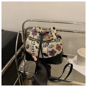 Close-up of vintage floral jacquard bucket bag with black leather base and drawstring