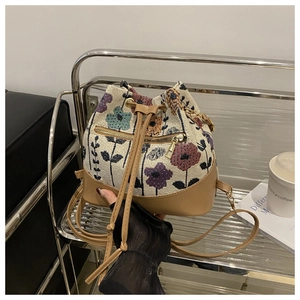 Detail of floral jacquard bucket bag showing beige fabric and brown leather textures