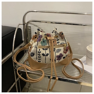 Close-up of floral canvas bucket bag with brown leather drawstring and golden hardware