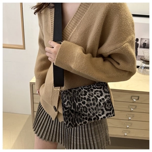 Détail d'un sac à bandoulière vintage à motif léopard avec une large sangle en tissu noir