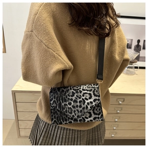 Fashionable leopard print shoulder bag with a wide woven strap for a trendy look