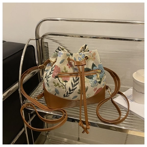 Detailed view of the drawstring bucket bag featuring floral jacquard fabric and PU base
