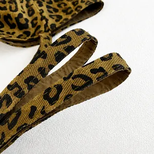 Macro detail of leopard print canvas shoulder strap with subtle gold metallic thread