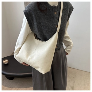 Detail of soft cream hobo bag with pleated leather texture on model's shoulder