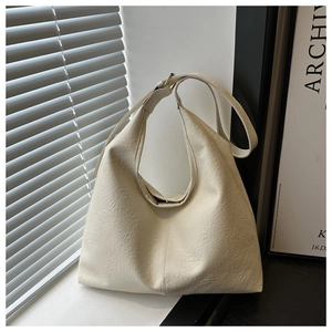 Detailed close-up of off-white hobo bag with pleated texture and adjustable strap
