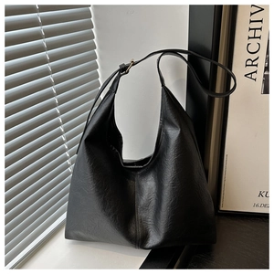 Detail of black vintage hobo bag showing pebbled texture and adjustable strap in soft light