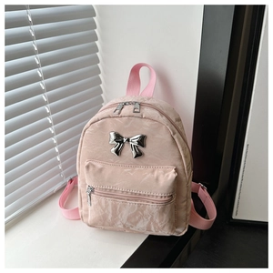 Detailed close-up of pink mini backpack featuring a silver metal bow and textured fabric