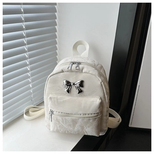 Detail of a mini cream backpack with marble-textured fabric and silver metal bow buckle