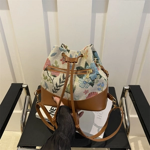 Ethnic embroidered bucket bag with floral patterns and brown leather strap detailing