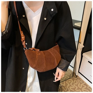 Détail d'un sac demi-lune en daim marron avec une bandoulière à nœud décoratif